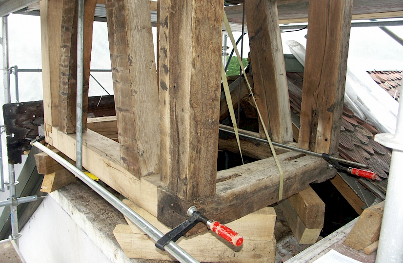Suite à la découverte de pourriture, le remplacement intégral des éléments de charpente touchés s’est avéré indispensable. Le beffroi est étayé de façon à dégager les traverses d’appui.
