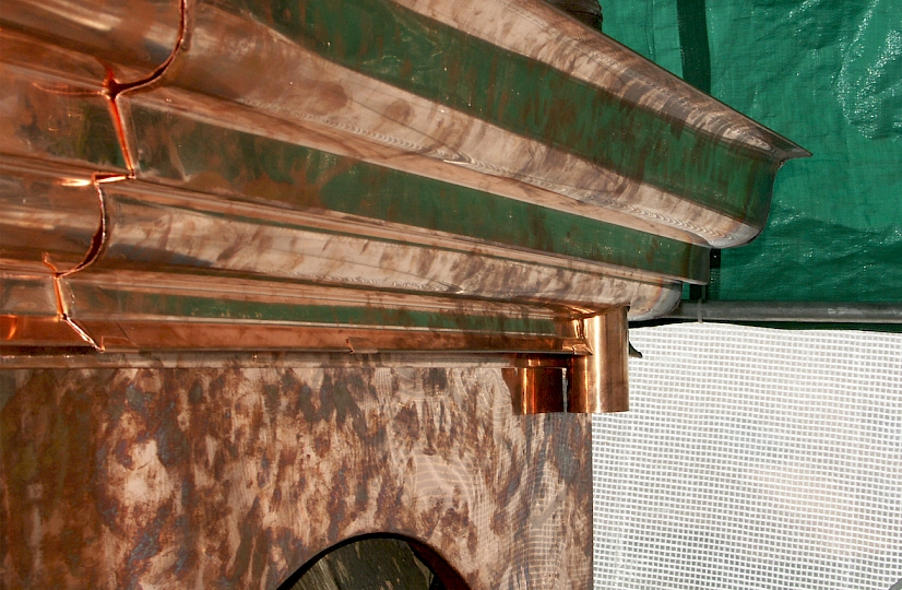 Vue sur le chéneau encaissé avec la moulure sous chéneau et la naissance de descente EP. Les crochets de fixation du chéneau ne sont plus apparents