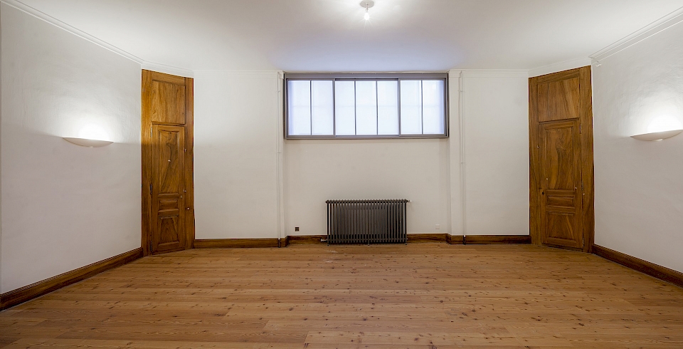 Le vitrage visible au centre, constitue la partie inférieure de la grande baie centrale donnant sur la rue Tabazan. Après restauration et remplace- ment des verres industriels jaune foncé par des verres clairs, la serrurerie a été rénovée et motorisée pour une facilitation d’ouverture, et la fenêtre a été doublée avec une double fenêtre en bois. Photo après travaux.