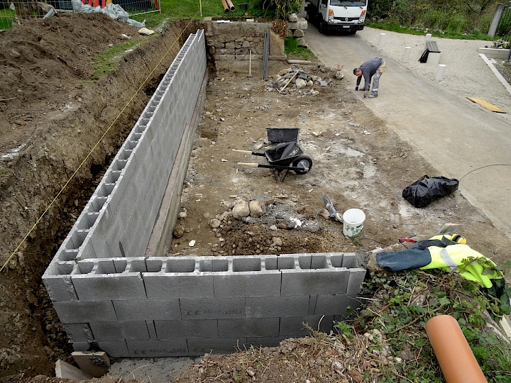 Construction en limite de parcelle communale du nouveau mur de contention en plot de ciment à bancher.