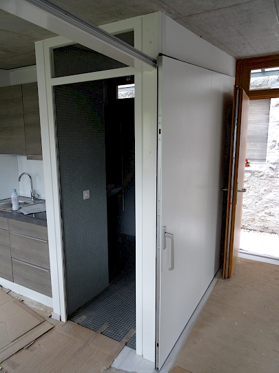 Système de porte coulissante trapézoïdale avec rail d'appui au sol et rail de guidage en partie supérieure.