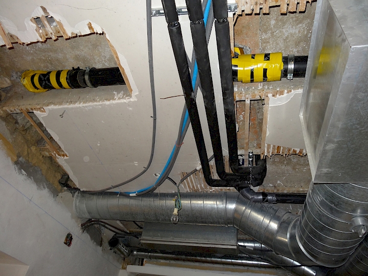 Installation d'un écoulement et de conduites d'alimentations en eau dans le local cuisine en vue des aménagements prévus dans la nef. Les gaines de ventilations visibles au plafond sont en place depuis les années 80.