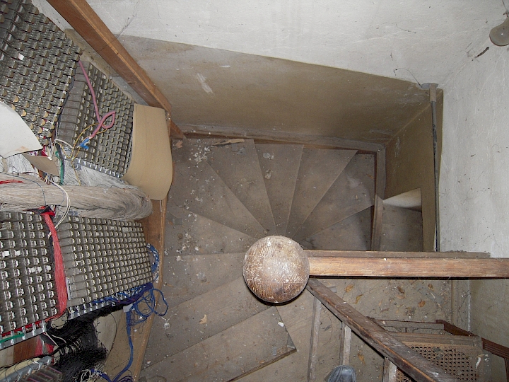 Vue plongeante sur l'escalier du beffroi au niveau de la galerie. A gauche, partie du mécanisme de l'orgue.