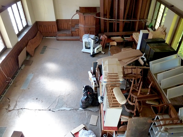 Vue d'ensemble de la nef en direction de la chaire. La dalle sur rez-inférieur est fendue sur toute la largeur au droit du mur de refend. Les boiseries, portes et fenêtres sont relativement bien conservés, à l'exception d'une partie des vitraux de la façade nord. Ces derniers n'ont pas résisté aux mouvements de la Chapelle.